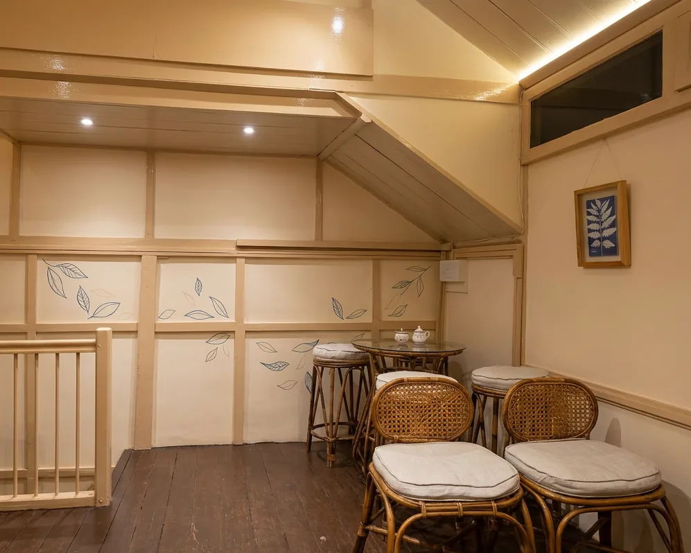 Upstairs corner seating nook with hand-painted tea-leaf motifs and cane bar stools